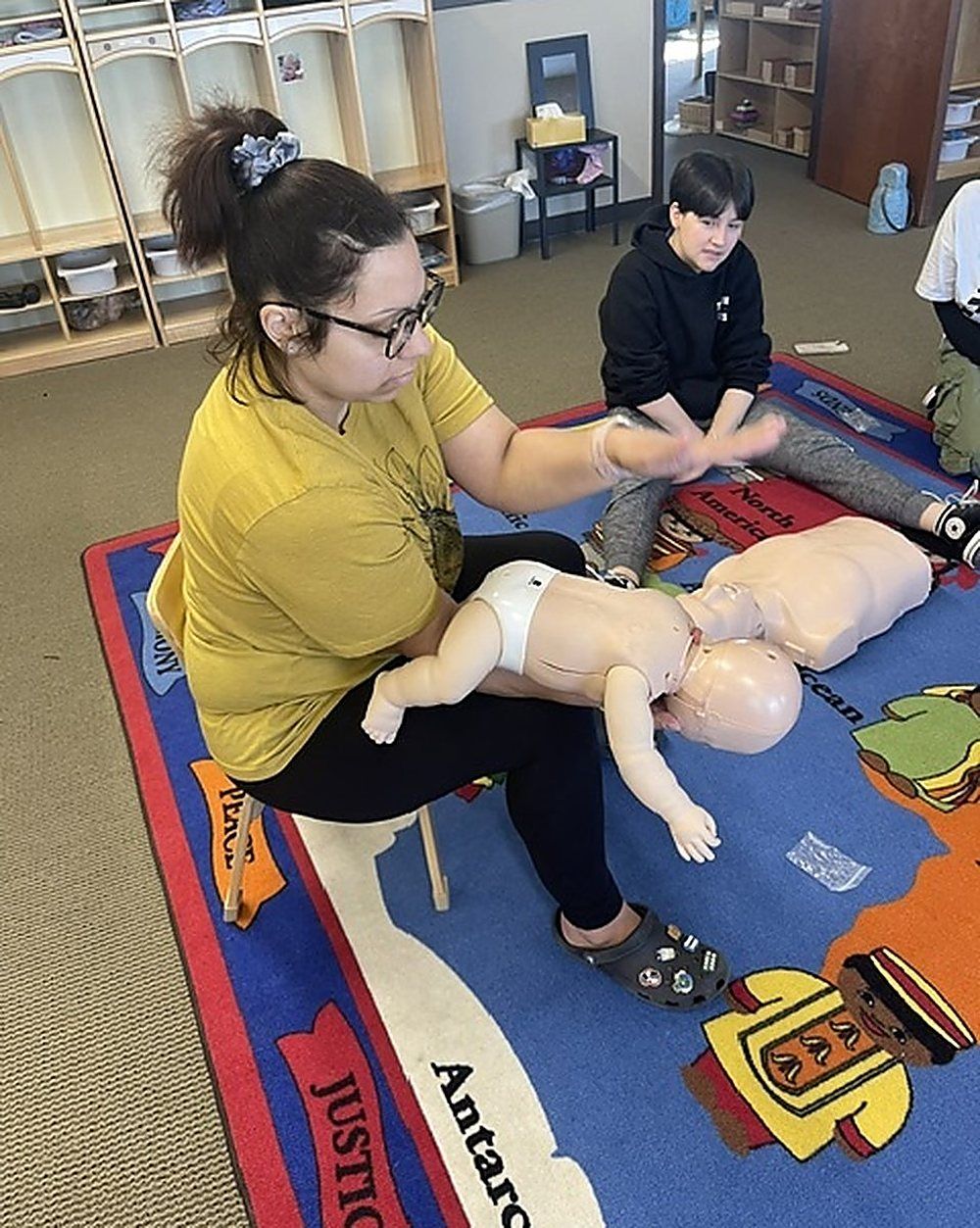 Manikins, bag valve masks and an AED trainer laid out on a training mat