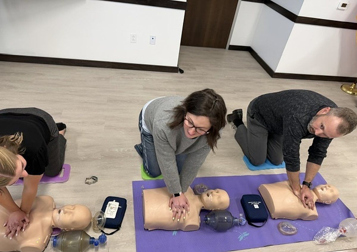 A workplace team practicing chest compressions on manikins