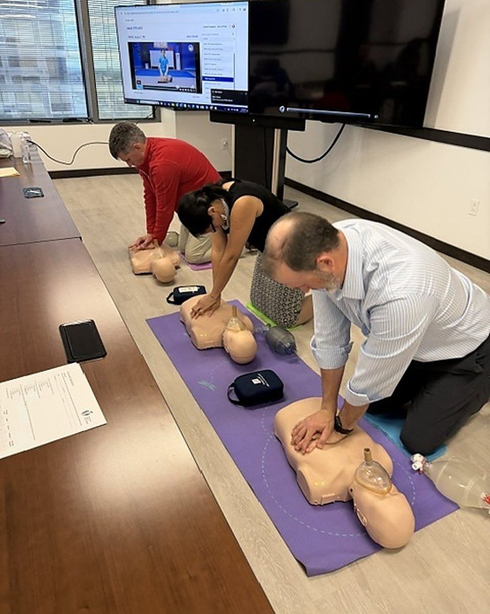 Manikins, bag valve masks and an AED trainer laid out on a training mat