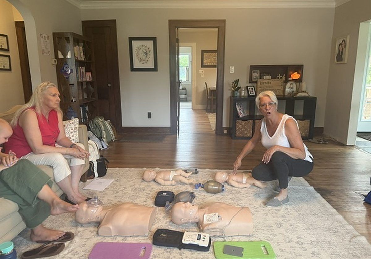 Pam Goldsberry with a group of guests and manikins on a living room floor